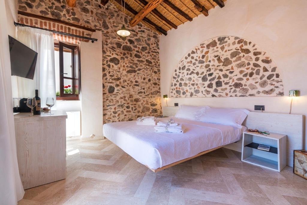 a bedroom with a large bed and a stone wall at Domo Pro Vois in Orosei