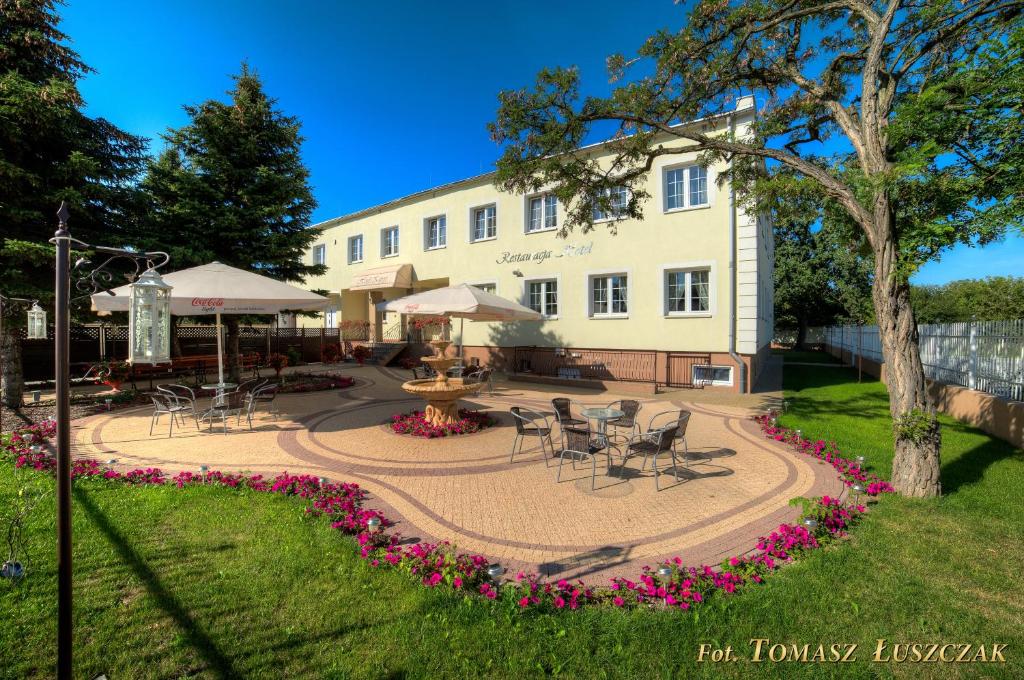 un edificio con un patio con sillas, mesas y flores en Hotel Kaprys, en Świdnik