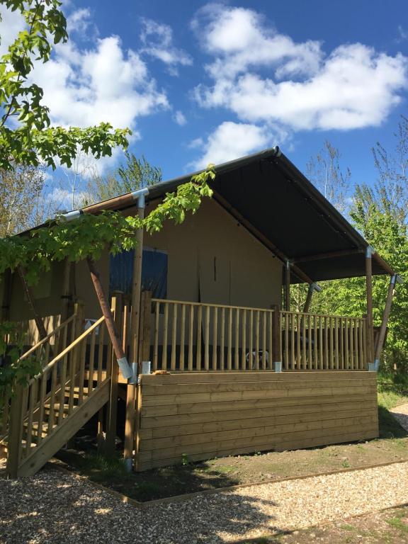 Talaton的住宿－Riverwood Farm Glamping Safari Tent，小屋设有黑色屋顶和木栅栏