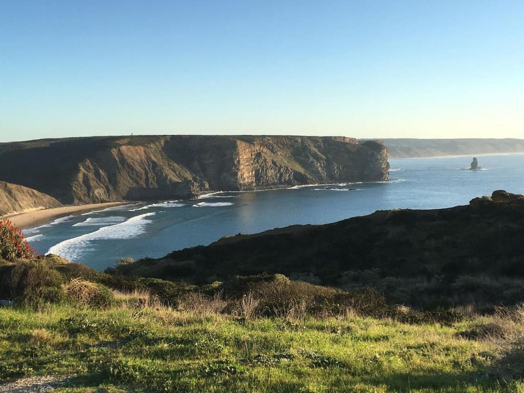 uma vista de uma praia com um barco na água em Varandas - Arrifana, com piscina, junto à praia em Praia da Arrifana