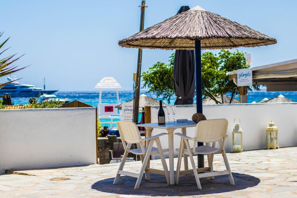 stół z 2 krzesłami i parasolem w obiekcie Romantika w mieście Platis Gialos Mykonos