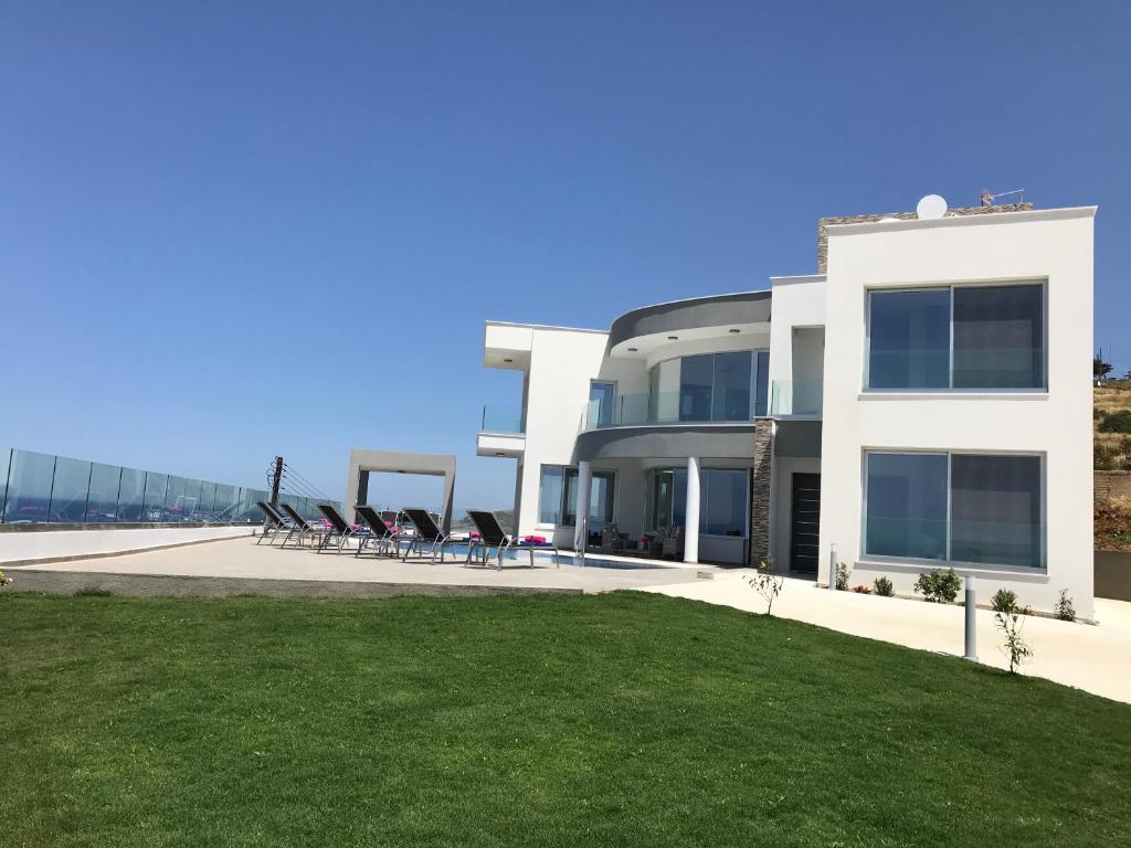 una gran casa blanca con césped delante en Elite Sea View Villa, en Pomos