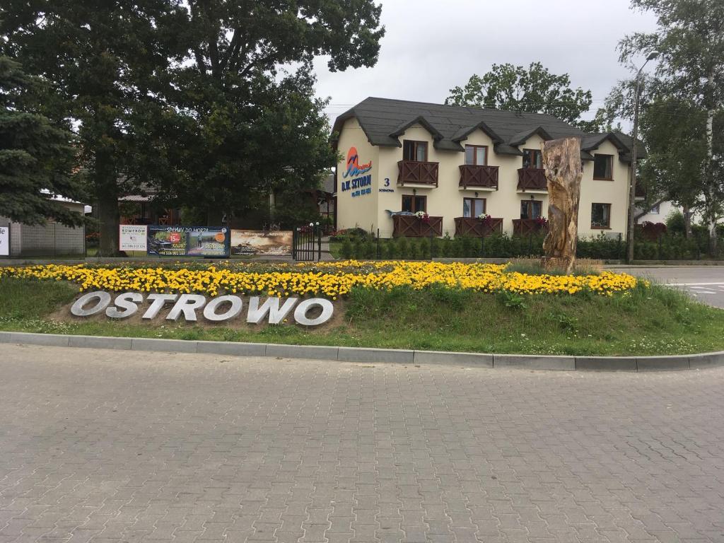 a sign in front of a building with flowers at Dom Wypoczynkowy Sztorm in Ostrowo