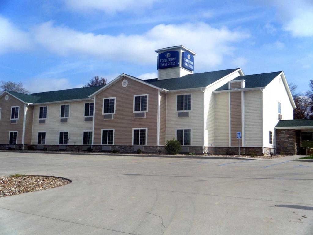 a large white building with a clock tower on top at Cobblestone Inn & Suites - Bloomfield in Bloomfield