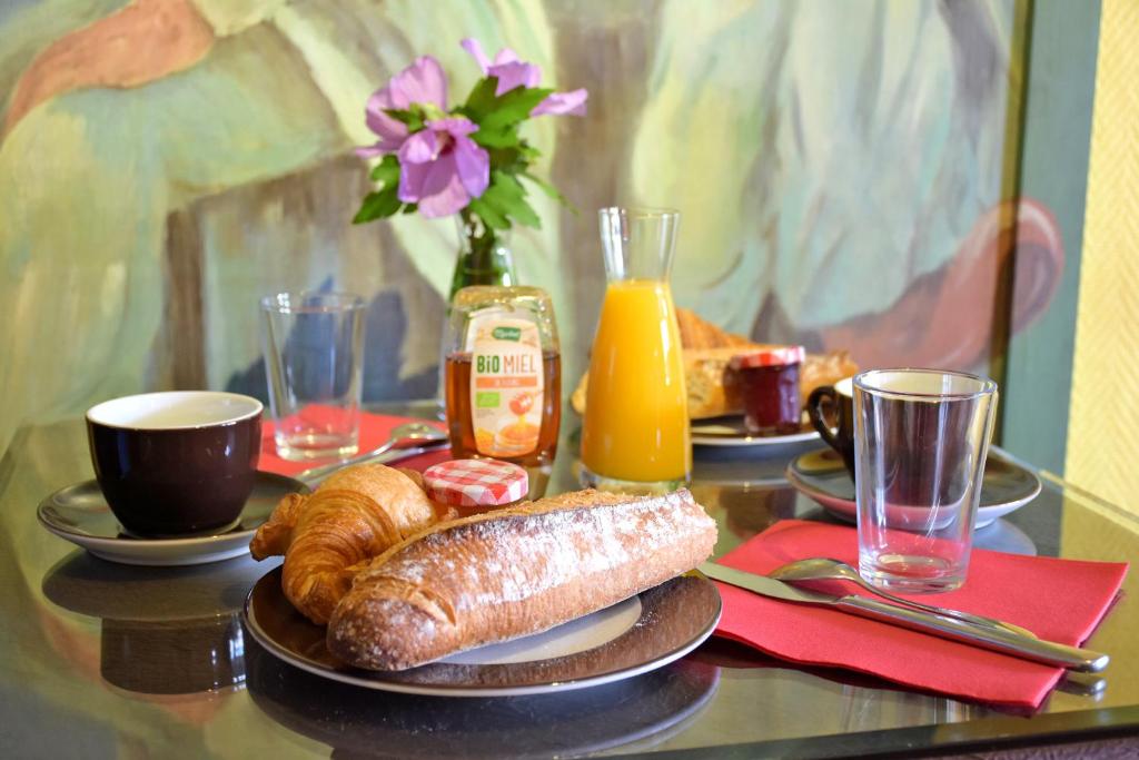 einen Tisch mit einem Frühstück mit Brot und Orangensaft in der Unterkunft Ad Cyber-Hôtel in LʼUnion