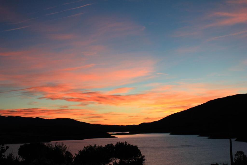una puesta de sol sobre un cuerpo de agua con montañas en Finca El Destino, en El Berrueco