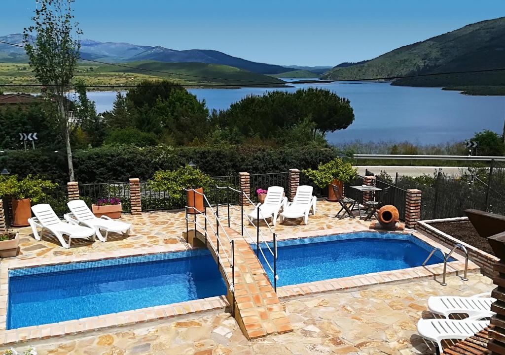 a pool with chairs and a view of a lake at Finca El Destino in El Berrueco