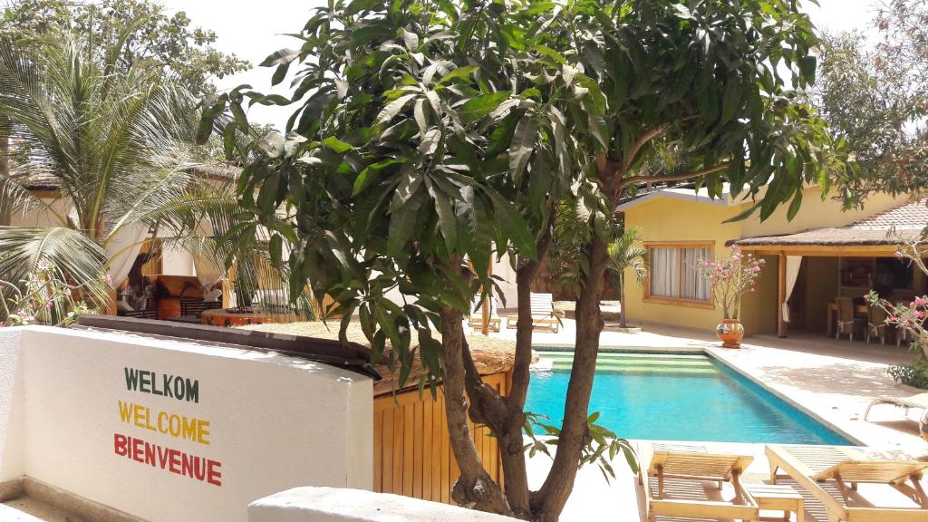 a swimming pool with a tree next to a house at B & B Teranga Warang in Ouoran