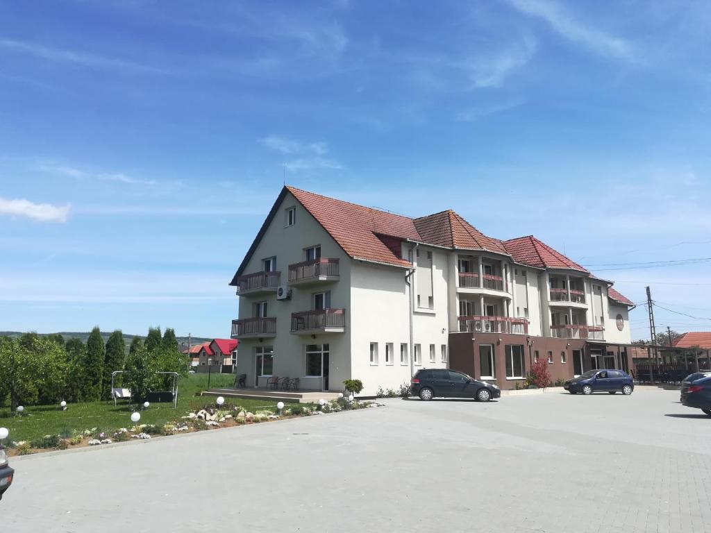 a large building with cars parked in a parking lot at Vila Gong in Gilău