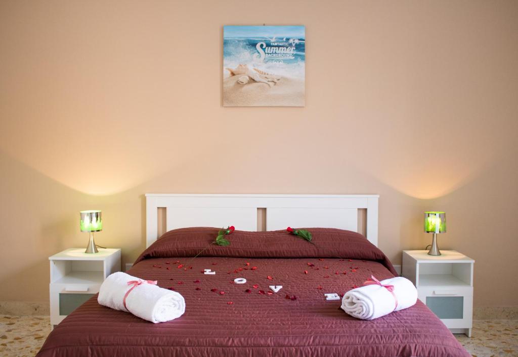 a bedroom with a bed with red sheets and white towels at UMBERTO I APARTMENTs in Bagheria