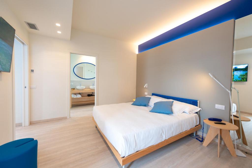 a bedroom with a large bed with a blue accent wall at Amarina Hotel in Marina di Pietrasanta