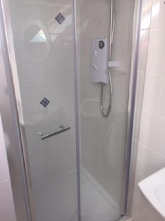 a shower with a glass door in a bathroom at Teach Beag Cois Tra in Miltown Malbay