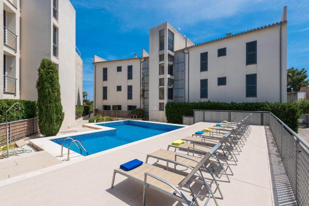 una piscina con mesas y sillas junto a los edificios en Residencial Llenaire Apartment, en Puerto Pollensa