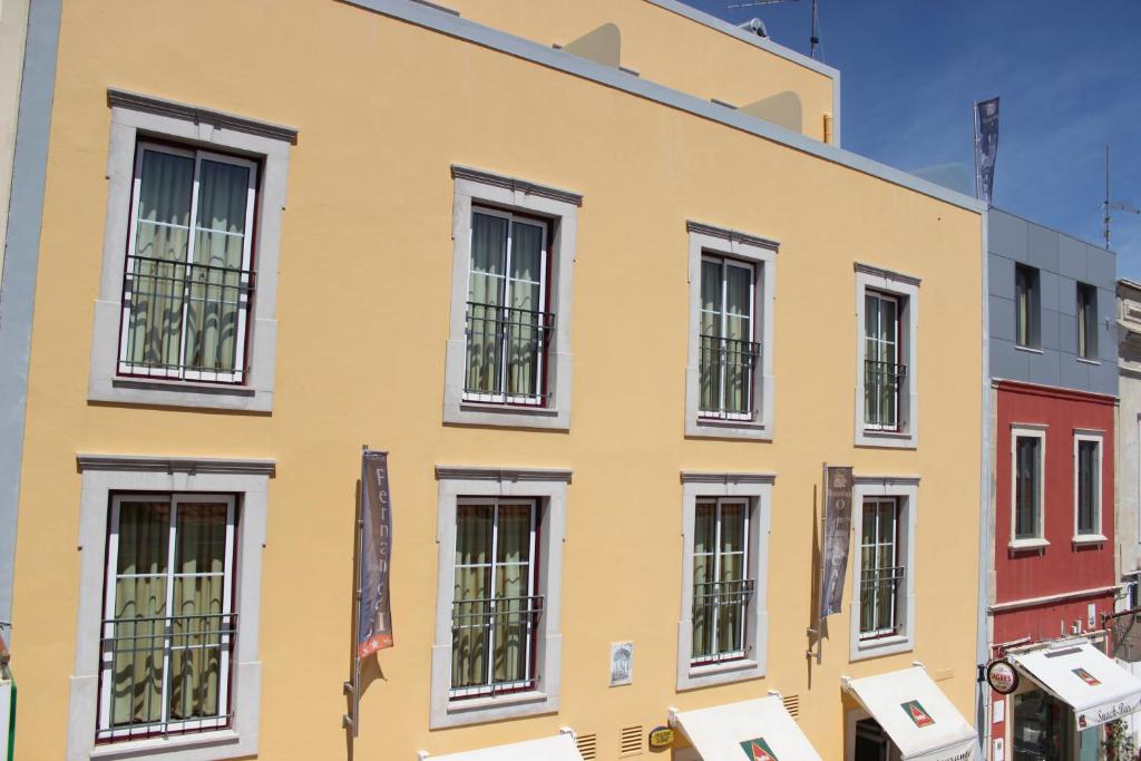 um edifício amarelo com janelas com barras pretas em Dom Fernando II em Loulé
