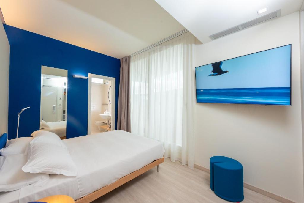 a bedroom with a white bed and a blue wall at Amarina Hotel in Marina di Pietrasanta