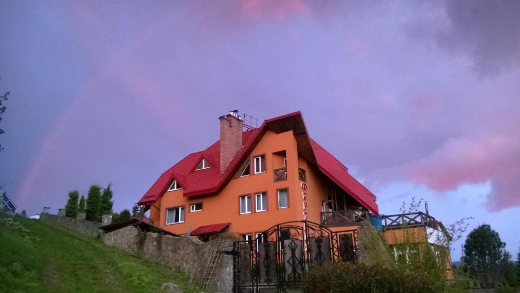 una gran casa naranja en una colina con un arco iris en el fondo en Hotel Fortetsya, en Slavske