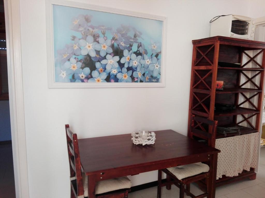 a dining room table with a painting on the wall at A casa di Nanè in Marina di Ragusa