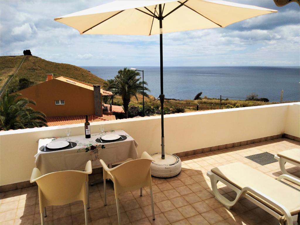 eine Terrasse mit einem Tisch und einem Sonnenschirm in der Unterkunft Beachfront House Atalaia in Caniço