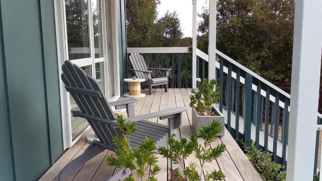 a porch with two chairs and plants on it at Four Huia in Oneroa