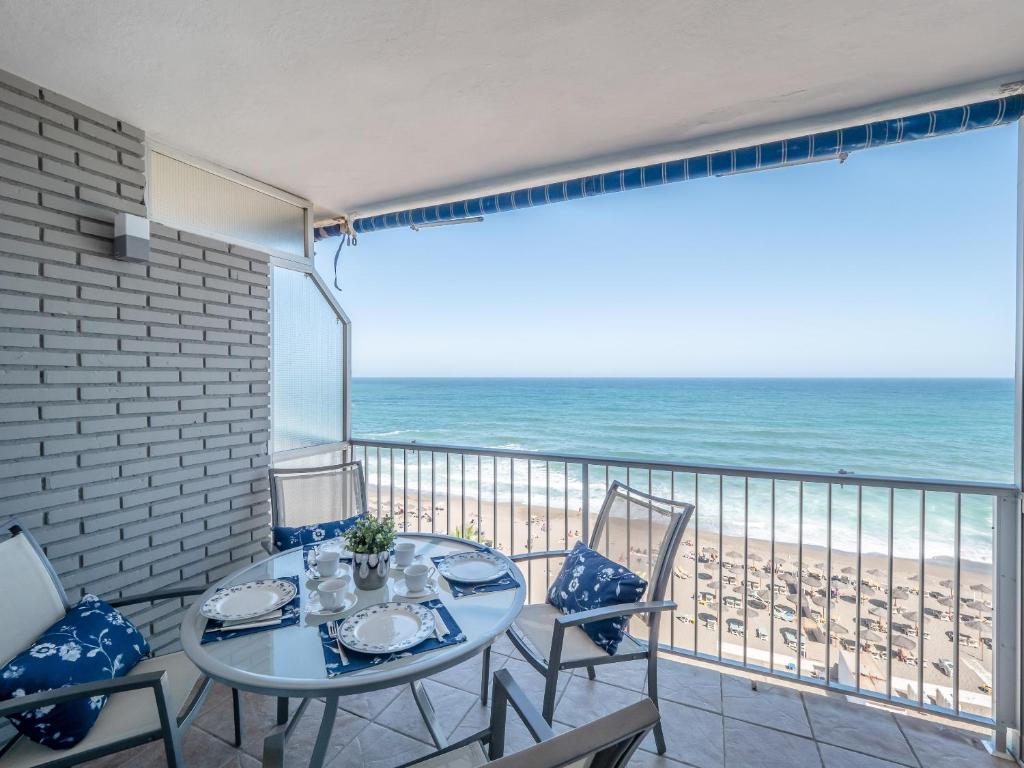 eine Terrasse mit Tisch und Stühlen sowie Strand in der Unterkunft SPECTACULAR SEA VIEW Fuengirola in Fuengirola