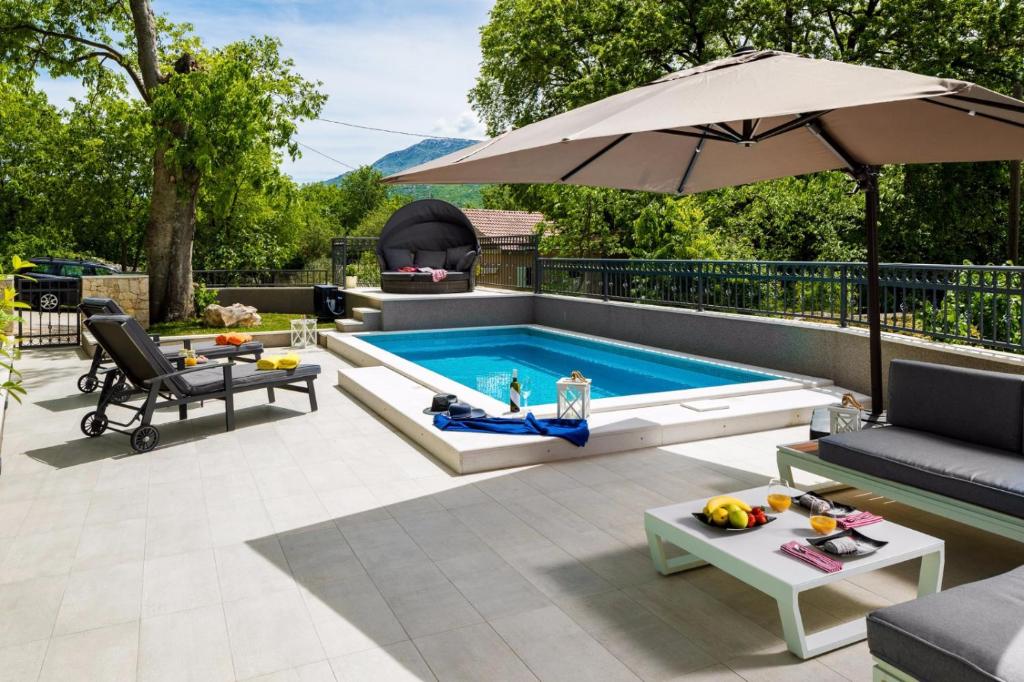 een zwembad met een parasol op een patio bij Modern and Cozy little House Mia in Dugopolje