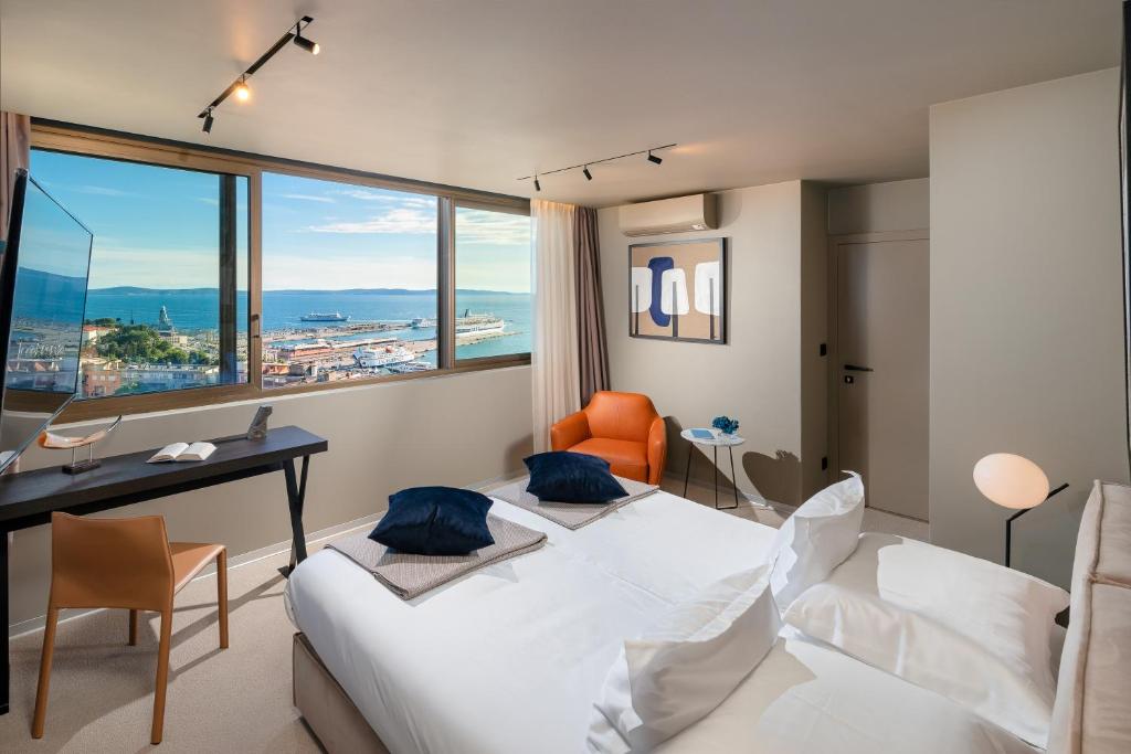 Cette chambre comprend un lit, un bureau et une fenêtre. dans l'établissement Royal Suites-Sky, à Split