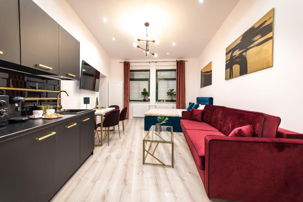 Una sala de estar con un sofá rojo y una cocina. en Golden Moonlight, en Zielona Góra