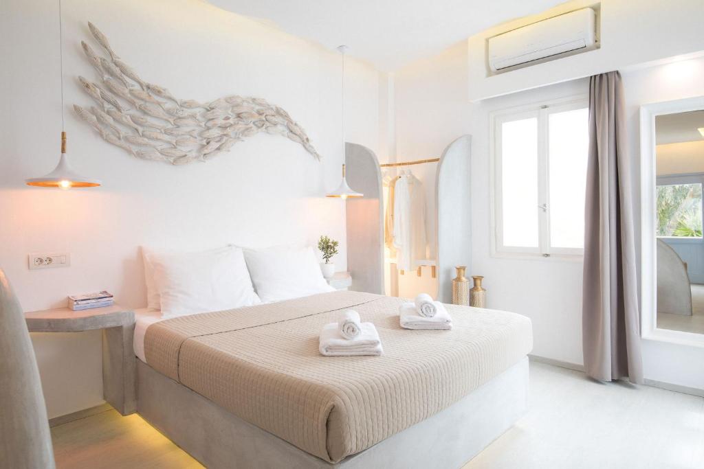 a white bedroom with a bed with towels on it at Light Blue Window Kamari in Kamari