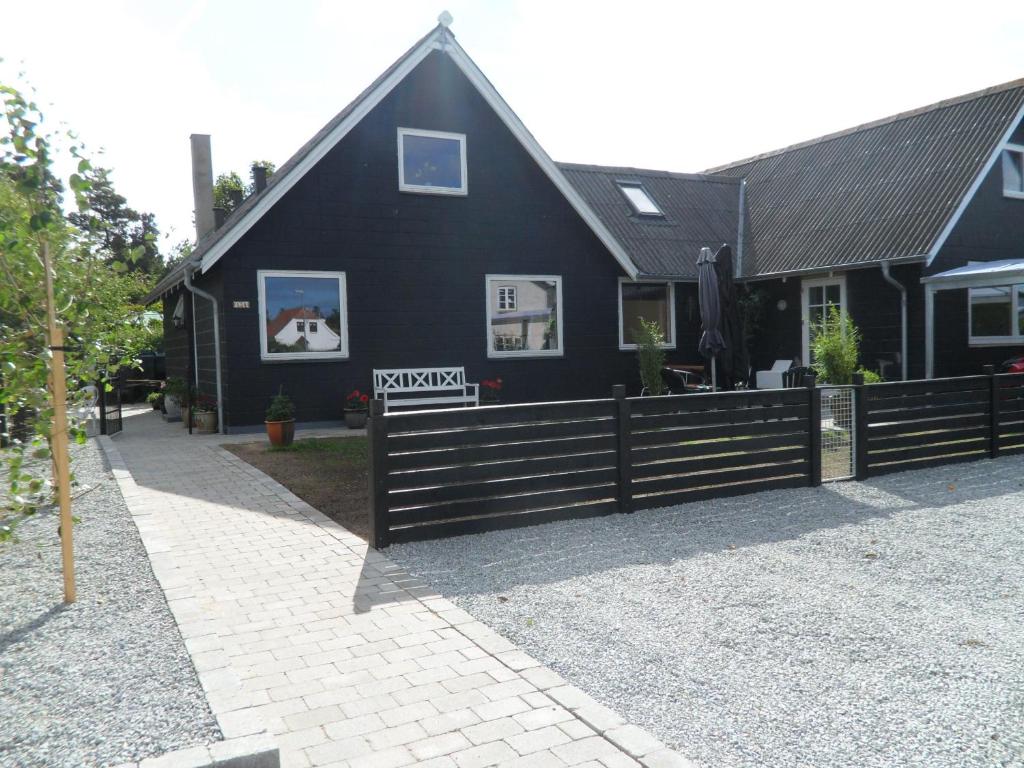 a black house with a fence in front of it at Hunetorpvej Holiday Apartment in Blokhus