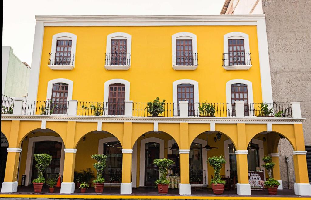 Best Western Hotel Madan في فيلاهيرموسا: مبنى أصفر مع شرفة ونصبات الفخار