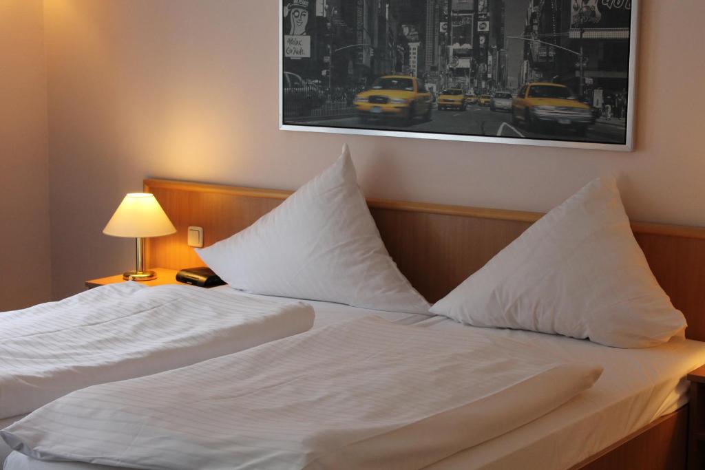 - un lit avec des oreillers blancs et une photo sur le mur dans l'établissement Filmhotel Lili Marleen, à Potsdam
