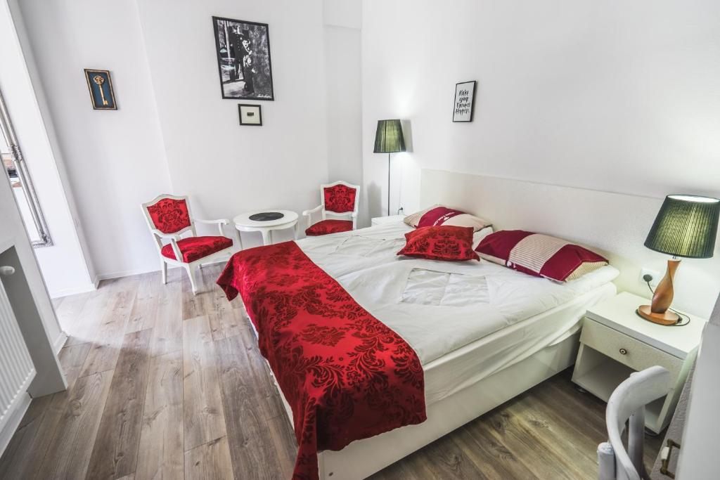 a bedroom with a bed and two red chairs at Silver Hotel in Tbilisi City