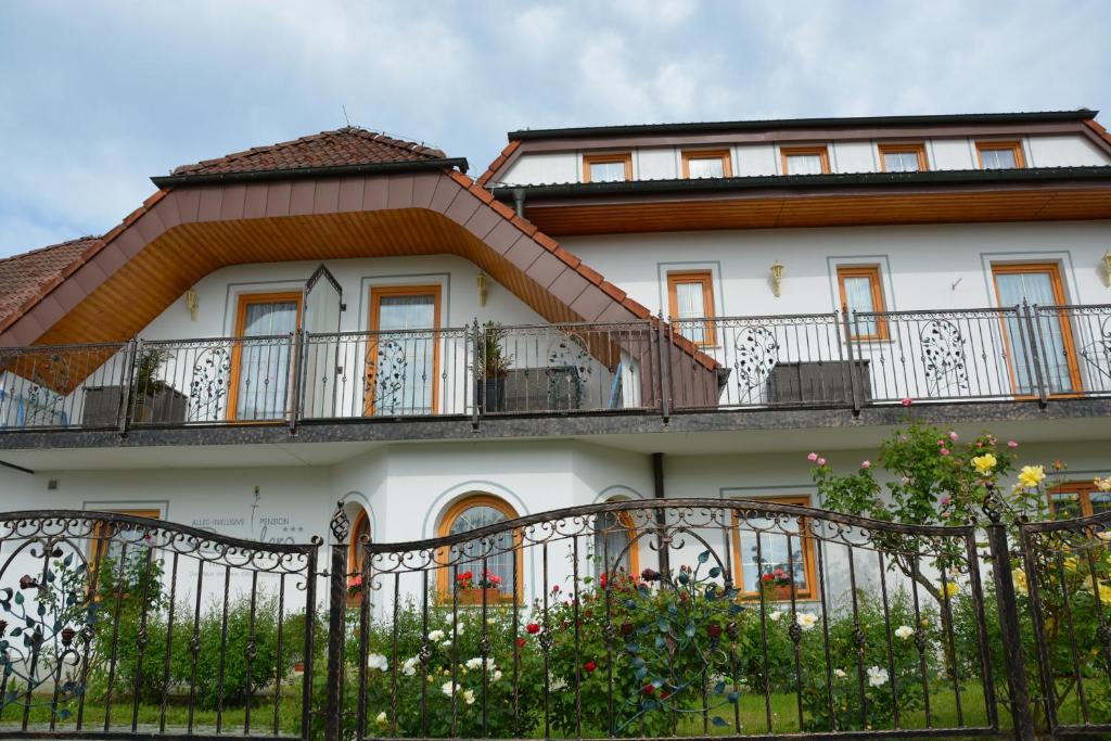 a white house with balconies and a fence at Pension Restaurant Rosenberg in Jennersdorf