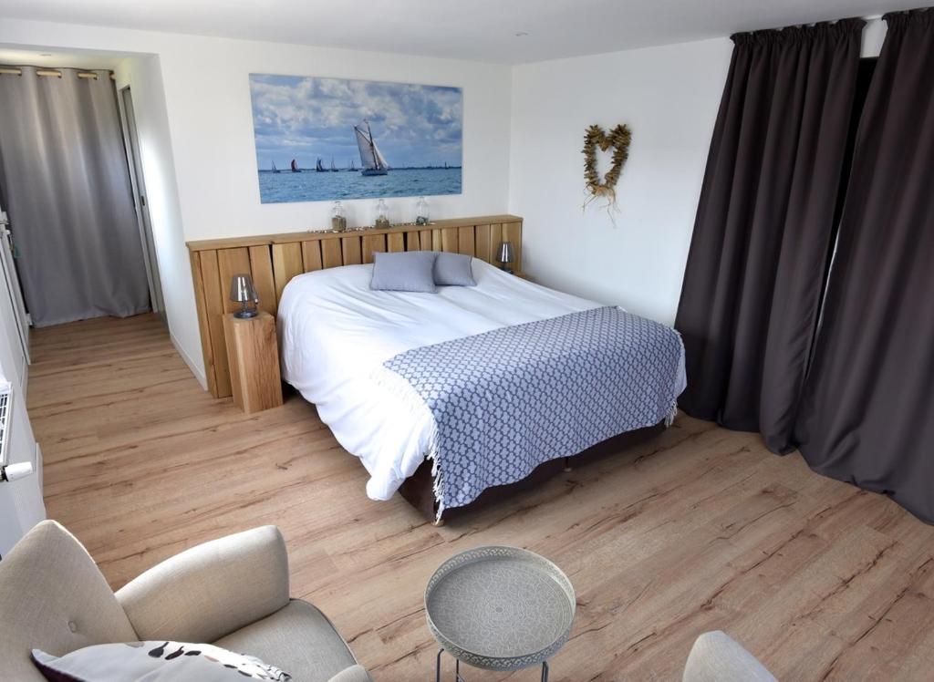 ein Schlafzimmer mit einem Bett, einem Sofa und einem Stuhl in der Unterkunft Petite Emeraude in Cancale