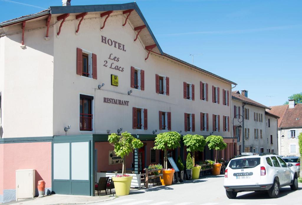 a building with a car parked in front of it at Hotel Les 2 Lacs in Clairvaux-les-Lacs