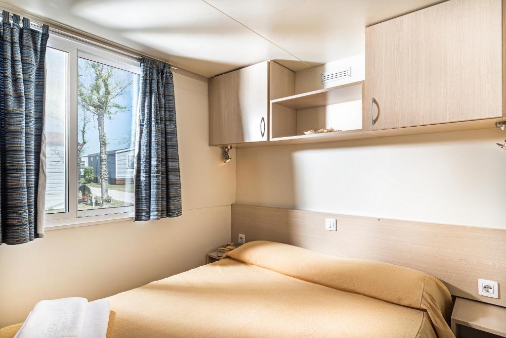 a small bedroom with a bed and a window at Villaggio San Francesco in Duna Verde