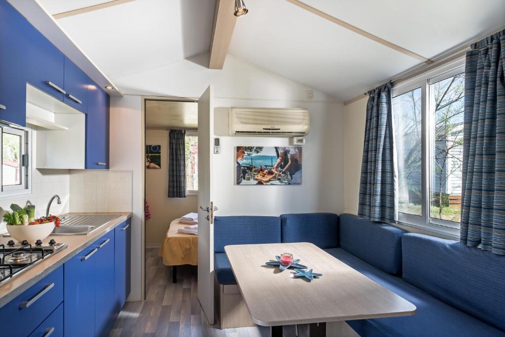 a kitchen with a blue couch and a table at Villaggio San Francesco in Duna Verde