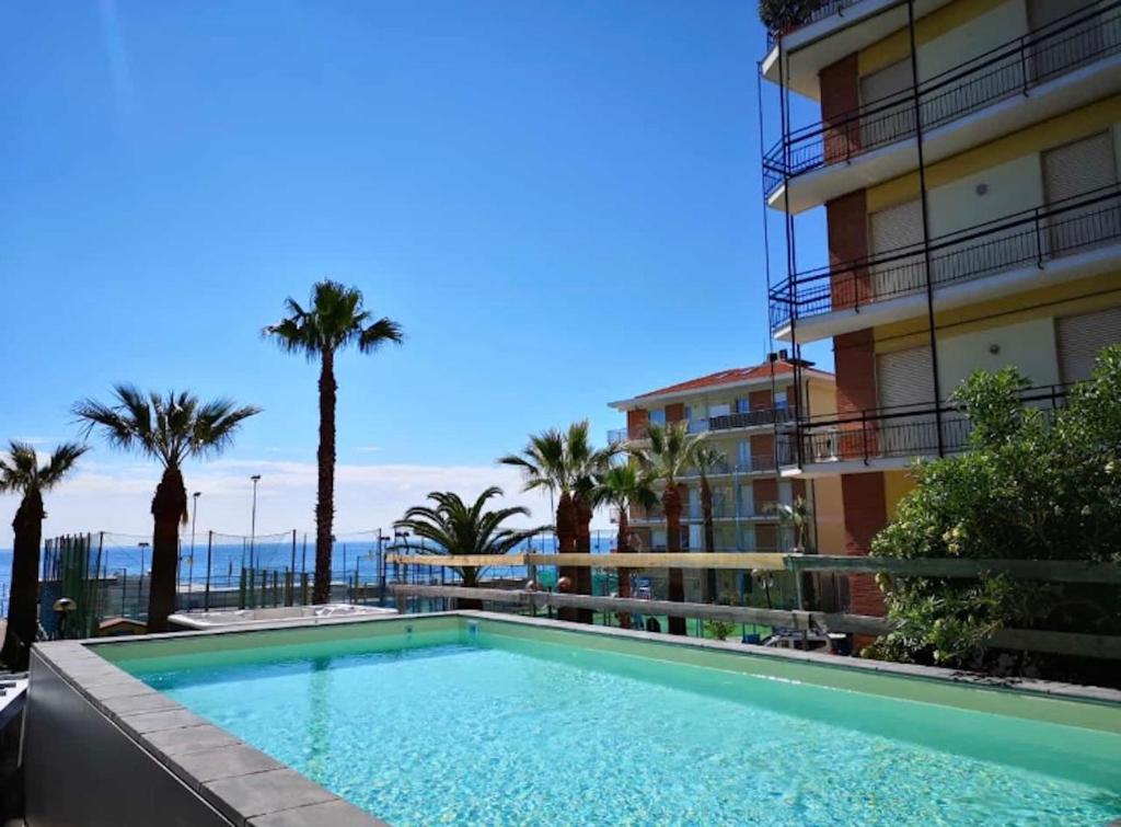 einem Pool vor einem Gebäude mit Palmen in der Unterkunft Hotel Lungomare in Marina dʼAndora