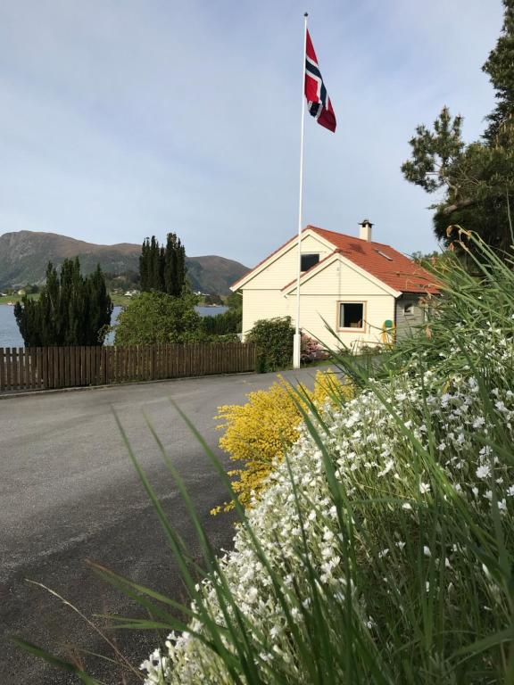a house with a flag on the side of a road at Skogstad Holiday Home in Selje
