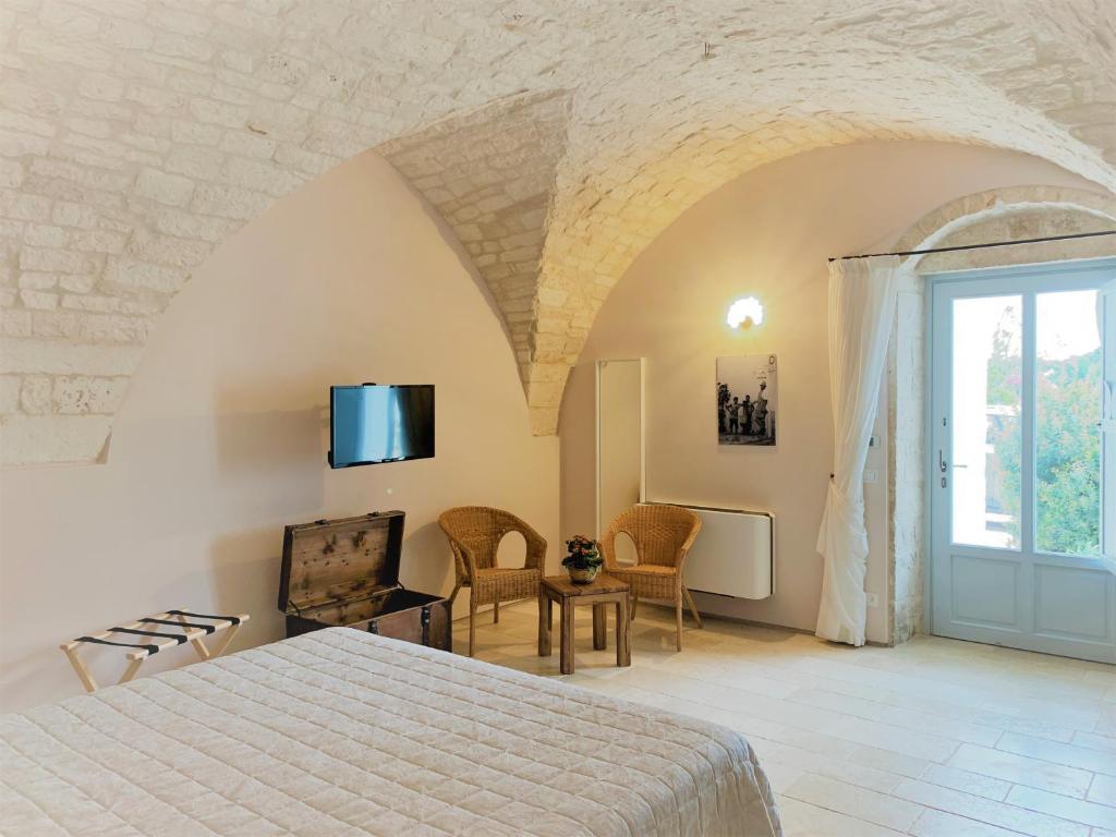 1 dormitorio con 1 cama y TV en la pared en Masseria Grofoleo, en Locorotondo
