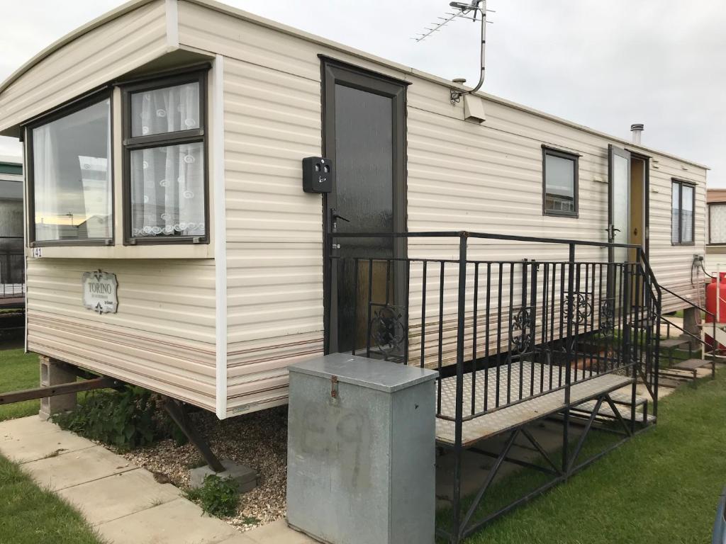 a white house with a black door and a porch at 6 berth Golden sands (Torino) in Ingoldmells