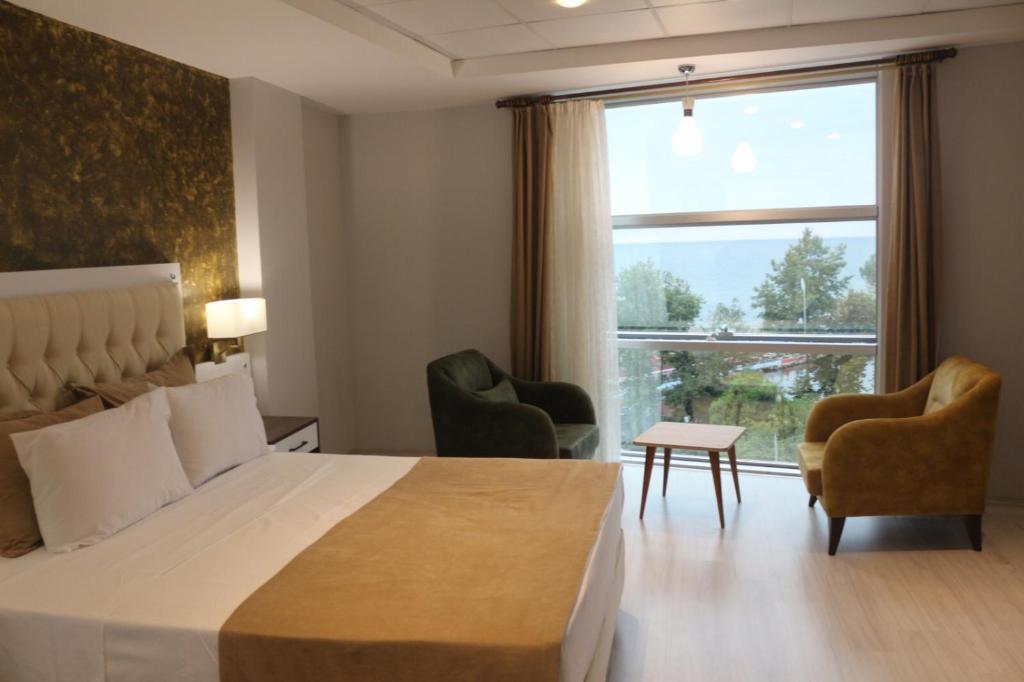 a hotel room with a bed and two chairs and a window at Alarga Premier Hotel in Trabzon