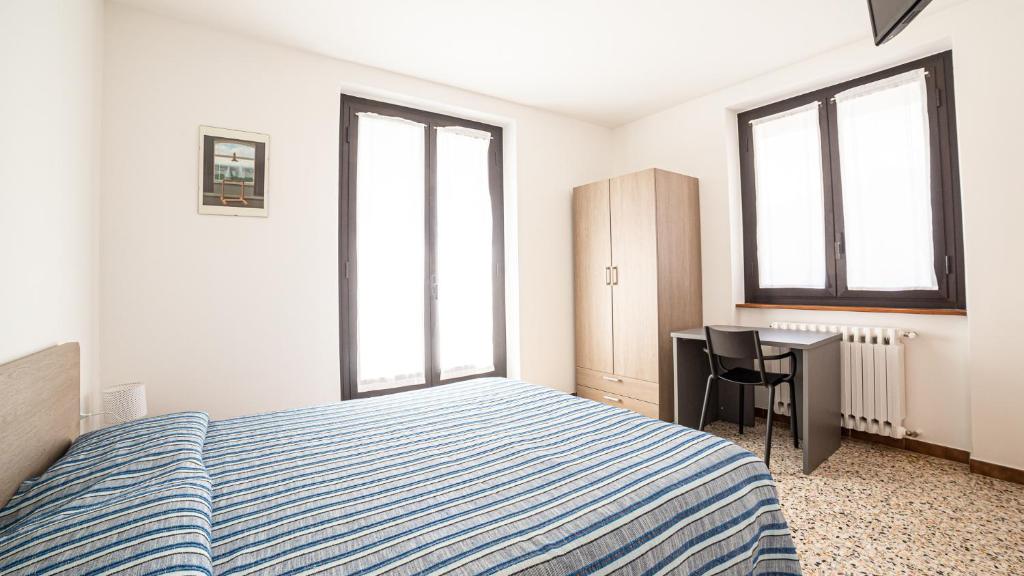 a bedroom with a bed and a desk and two windows at albergo bellavista in Re