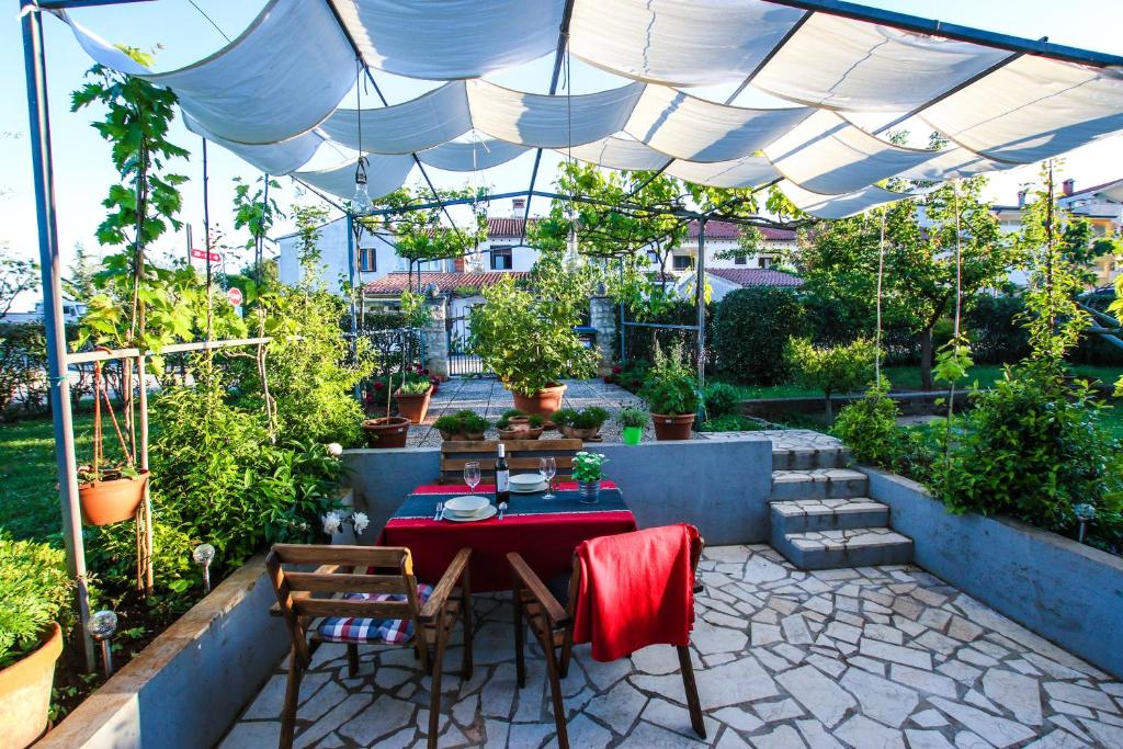 un patio con mesa y sillas bajo una sombrilla blanca en Apartment Lynn, en Poreč