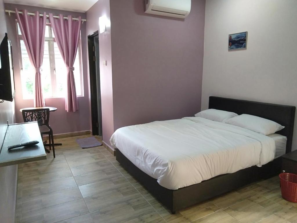 a bedroom with a bed and a desk and a window at Purple Dream Home in Teluk Panglima Garang
