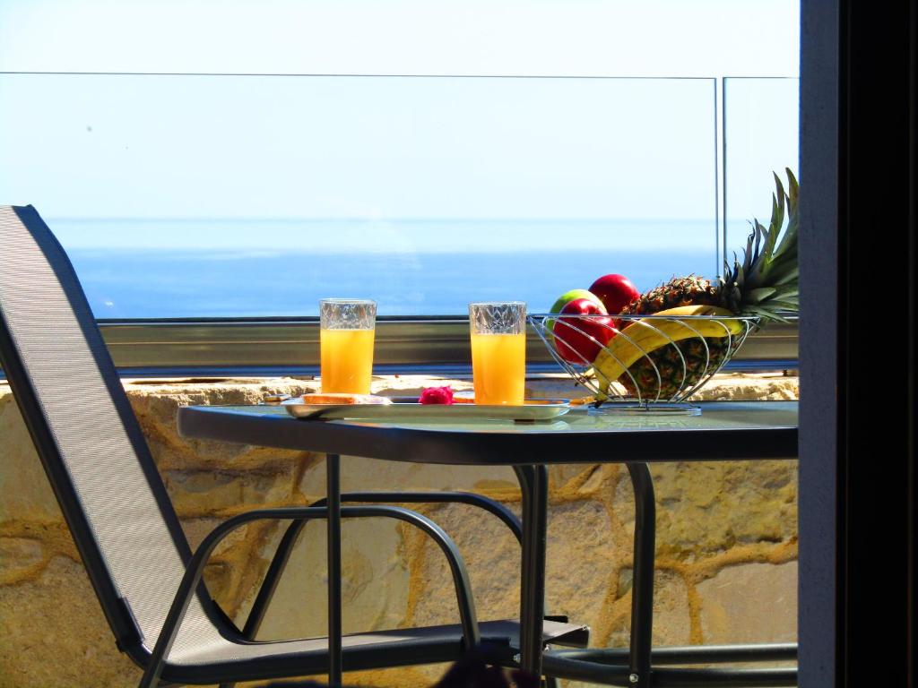 a table with two glasses of orange juice and a bowl of fruit at Aristos Apartments & Suites in Stalos