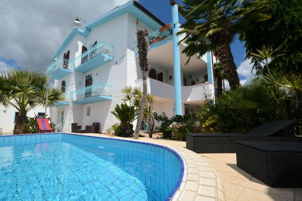 a house with a swimming pool in front of a building at Villa Dessena Guest House in Cala Liberotto