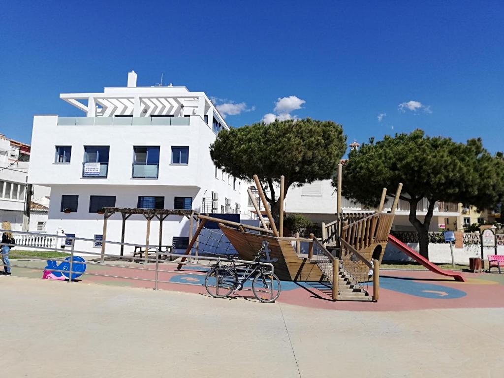 a playground in front of a white building at Apartamentos Varadero On the beach in Cala del Moral