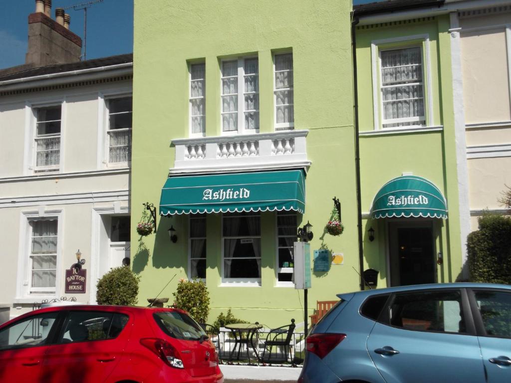 two cars parked in front of a green building at Ashfield Guest House in Torquay