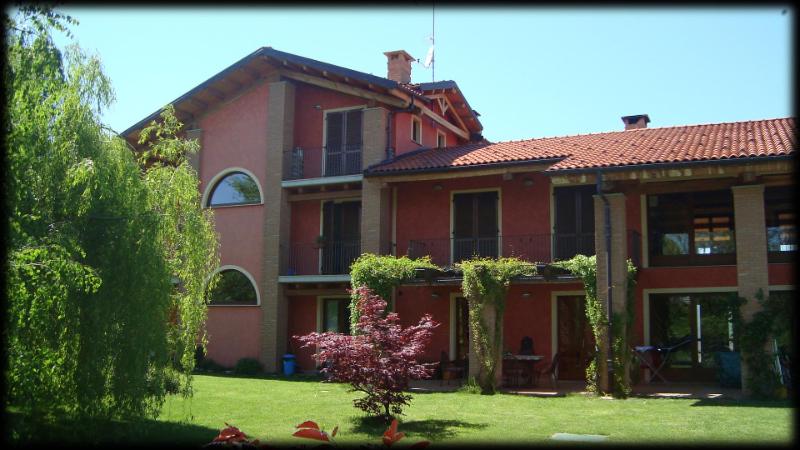 una grande casa rossa con un cortile verde di Bed & Breakfast Milù a Cuneo